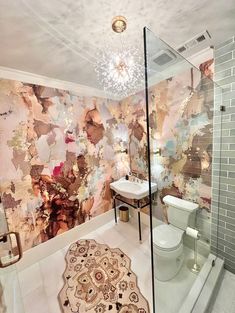 a bathroom with a white toilet sitting next to a walk in shower under a chandelier