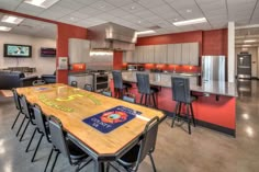 a large open kitchen and dining room area with red walls, wood flooring and stainless steel appliances