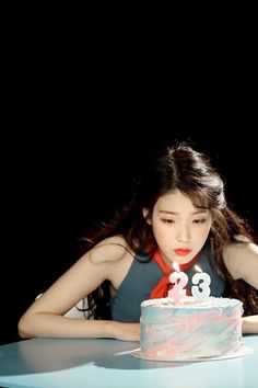 a woman sitting at a table with a cake in front of her