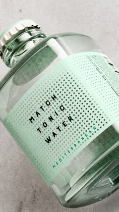 a close up of a bottle of water on a white surface with the words match tonic water written on it