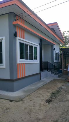 a man standing in front of a gray and orange house