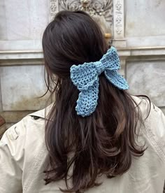 a woman wearing a blue crochet bow in front of a wall with carvings on it