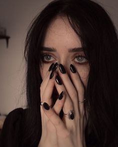 a woman with black nails covering her face