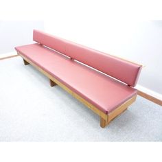 a pink bench sitting on top of a carpeted floor next to a white wall