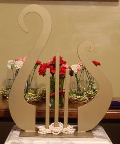 two vases with flowers in them are sitting on a marble base and one is shaped like the letter s