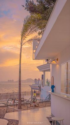 the sun is setting over the ocean and people are sitting at tables on the beach