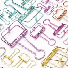 many different colored paper clips on a white surface