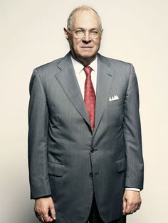 an older man in a suit and tie posing for a photo with his hands in his pockets