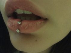 a close up of a person's nose with two piercings on the lip