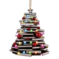 a christmas tree made out of books with lights on it's sides and an ornament hanging from the top