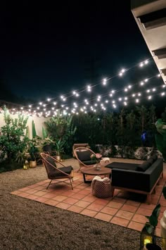 a patio with lights strung over it and furniture on the ground in front of them