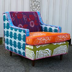 an upholstered colorful chair sitting in front of a white wall