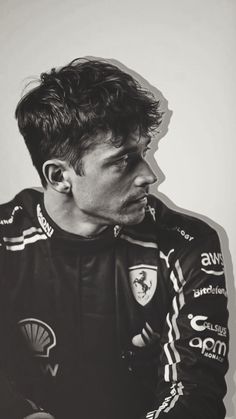 a black and white photo of a man in a racing suit looking to the side