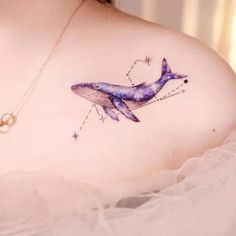 a woman's chest with a tattoo of a whale and stars in the sky