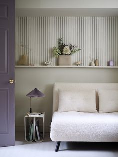 a white couch sitting next to a purple door