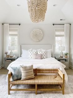 a bedroom with a large bed and chandelier hanging from the ceiling above it