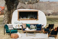 a living room area with chairs, couches and a camper in the background