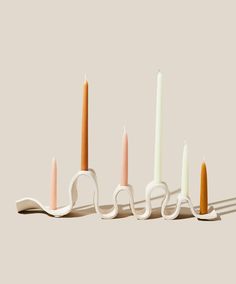 four candles are lined up in the shape of scissors with one candle sticking out of it