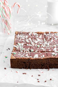 a chocolate cake with white and green sprinkles on it, surrounded by candy canes