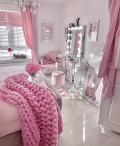 a bedroom decorated in pink and white with chandelier, bed, dresser, mirror and chair