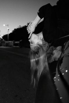 a woman leaning on the back of a car while holding onto another woman's head