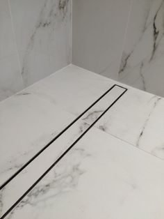 a bathroom with marble walls and flooring in the shower area, including two black lines