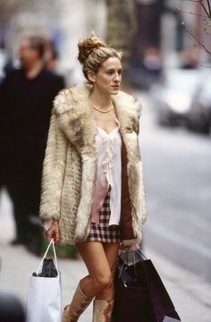 a woman is walking down the street with shopping bags in her hand and wearing boots