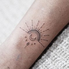 a small sun and moon tattoo on the left arm, with stars in the background