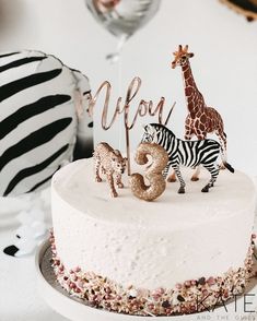 a zebra and giraffe cake topper on a white cake