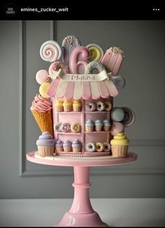 a pink cake with cupcakes and sweets on it's tiered stand