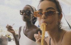 two women are eating spaghetti together outside