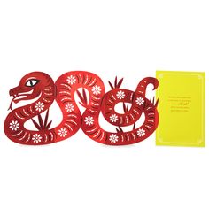 a red paper cut snake next to a yellow card