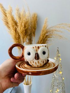 a hand holding a coffee cup with an owl design on it