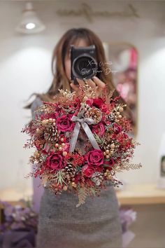 a woman holding a camera taking a photo with her bouquet in front of her face