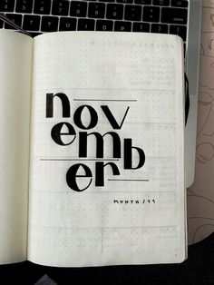 an open notebook with the words november written in black on it next to a keyboard