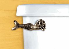 there is a metal mermaid on the toilet