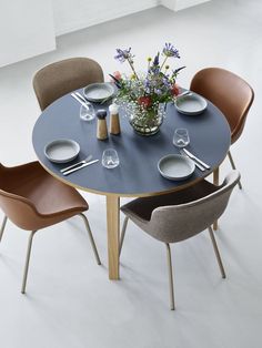 a round table with four chairs around it and a vase filled with flowers on top