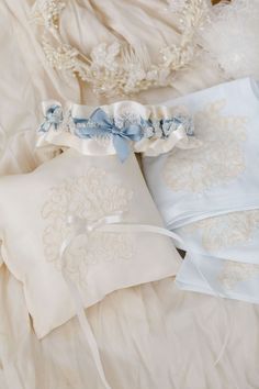 two wedding garters are laying on top of a white bed sheet with blue ribbons