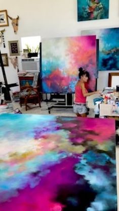 a woman painting in an art studio with colorful paint on the canvass and floor