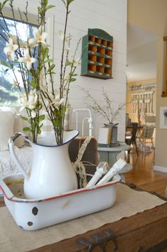 a white pitcher filled with flowers on top of a table