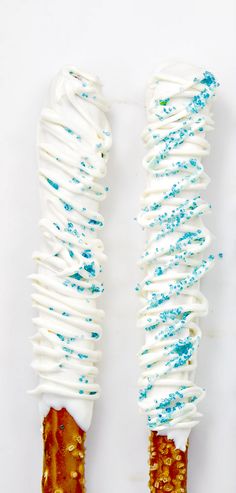 two candy sticks with white frosting and blue sprinkles