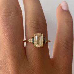 a woman's hand with a ring on it and an emerald stone in the middle