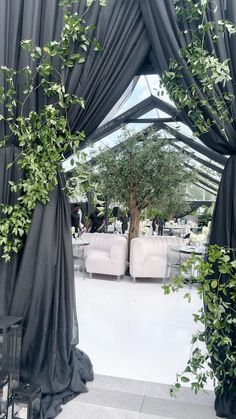 an open room with black drapes and greenery on the walls, as well as white couches