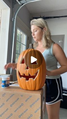 a woman standing next to a pumpkin on top of a box