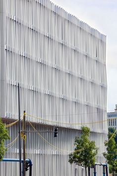 a tall building with white lines on it's side and trees in the foreground