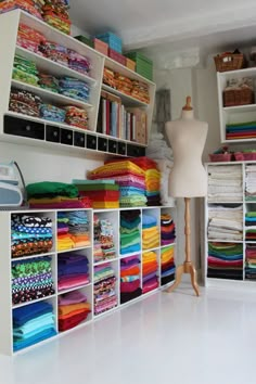 a room filled with lots of different types of fabrics and fabric on shelves next to a mannequin