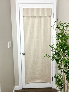 a white door with a beige vertical blind in front of it and a potted plant next to it