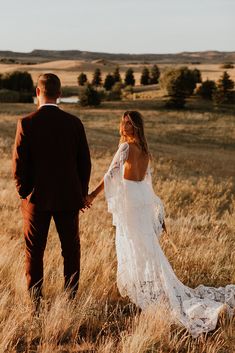 a bride and groom holding hands in the middle of an open field with tall grass