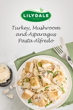 a white plate topped with pasta covered in mushrooms and sauce next to a knife and fork