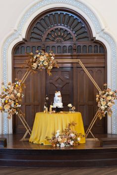 a table with a cake and flowers on it in front of a wooden entrance door